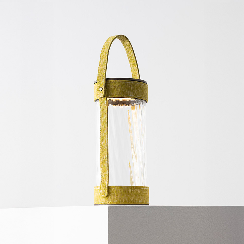 Artemide Laya portable lantern with cylindrical glass diffuser, visible filament LED, and yellow-green textile strap handle