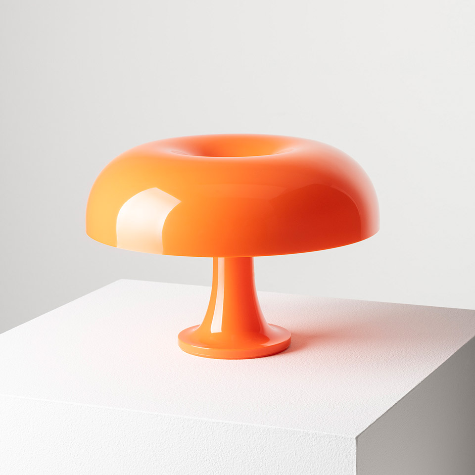 Artemide Nessino table lamp in orange, featuring a glossy donut-shaped shade on a slender pedestal base