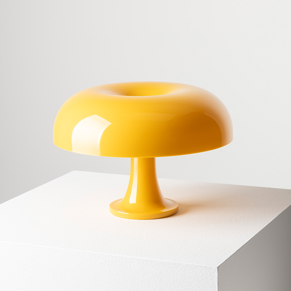 Artemide Nessino table lamp in glossy yellow, featuring a toroidal mushroom-shaped shade on a slender pedestal base