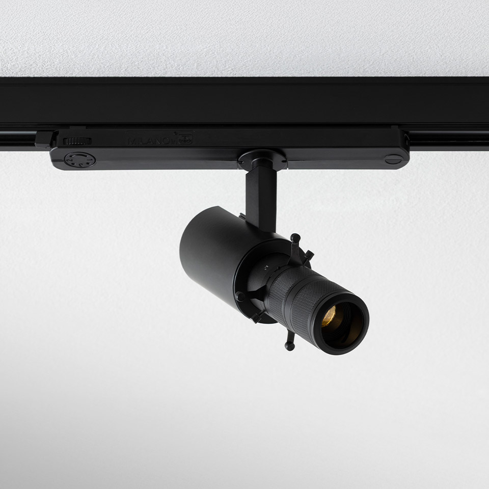 Artemide Vector Shaper black track spotlight with zoom lens, mounted on black ceiling rail, adjustable cylindrical LED projector