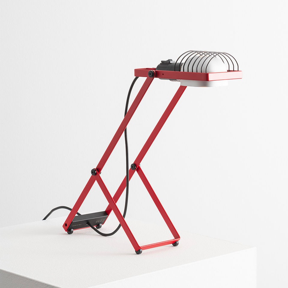 Artemide Sintesi table lamp in red with scissor-shaped metal frame, white reflector shade with protective grid, and black power cord