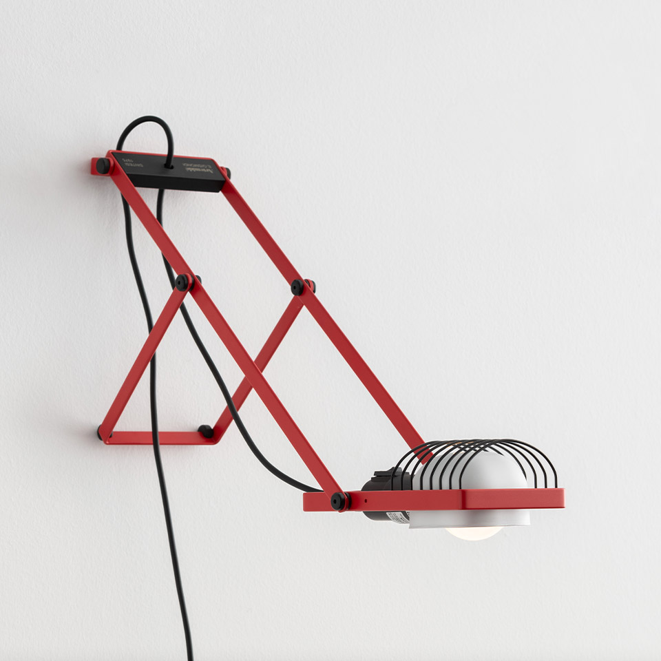Artemide Sintesi wall lamp in red with scissor-articulated arm, black wire cage shade, and exposed black power cord