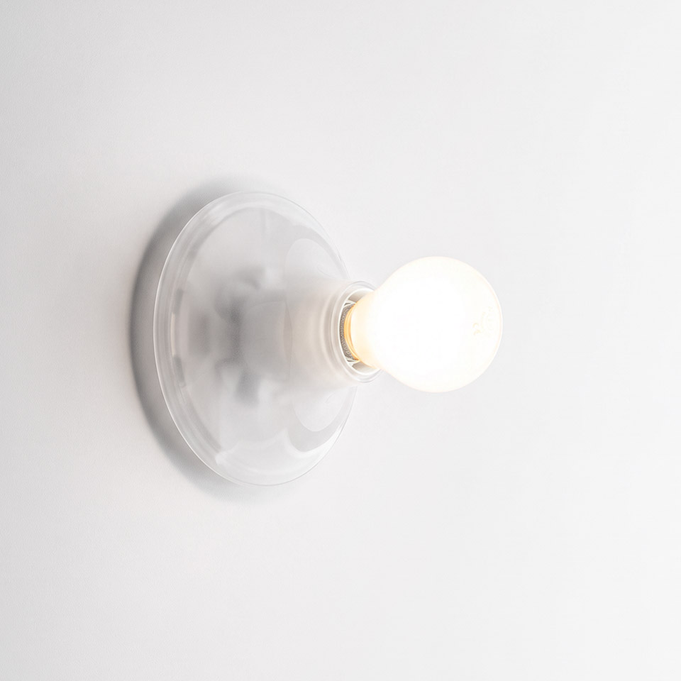 Artemide Teti wall sconce in white, featuring a round glossy base and a single exposed frosted globe bulb