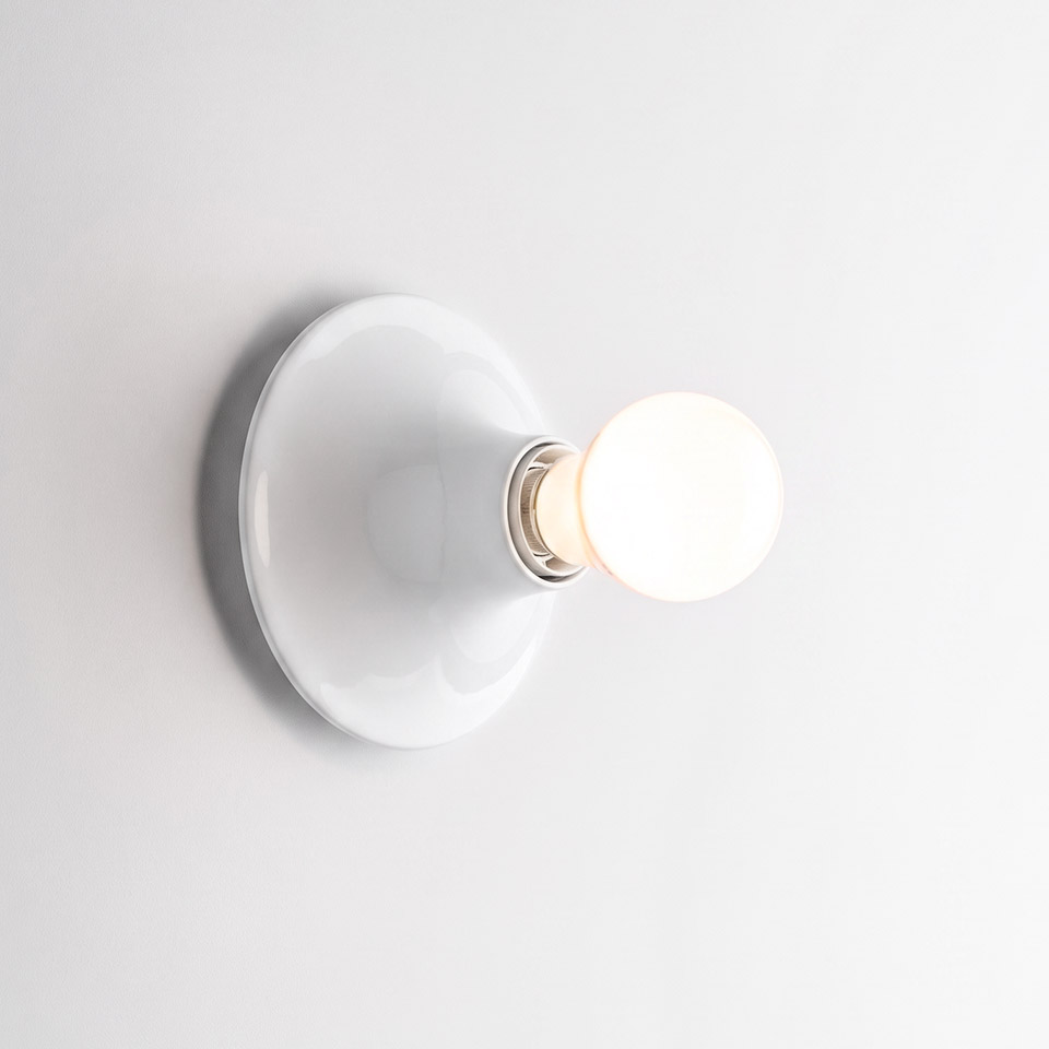 Artemide Teti wall lamp in white, featuring a round ceramic base and a single exposed frosted globe bulb