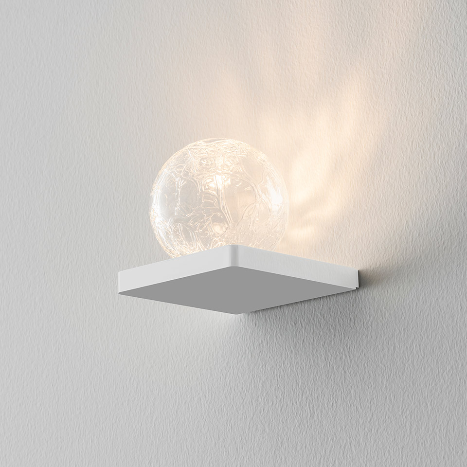 Artemide Ulrich und Diotima wall lamp: white square base with a textured crystal glass sphere emitting warm decorative light patterns