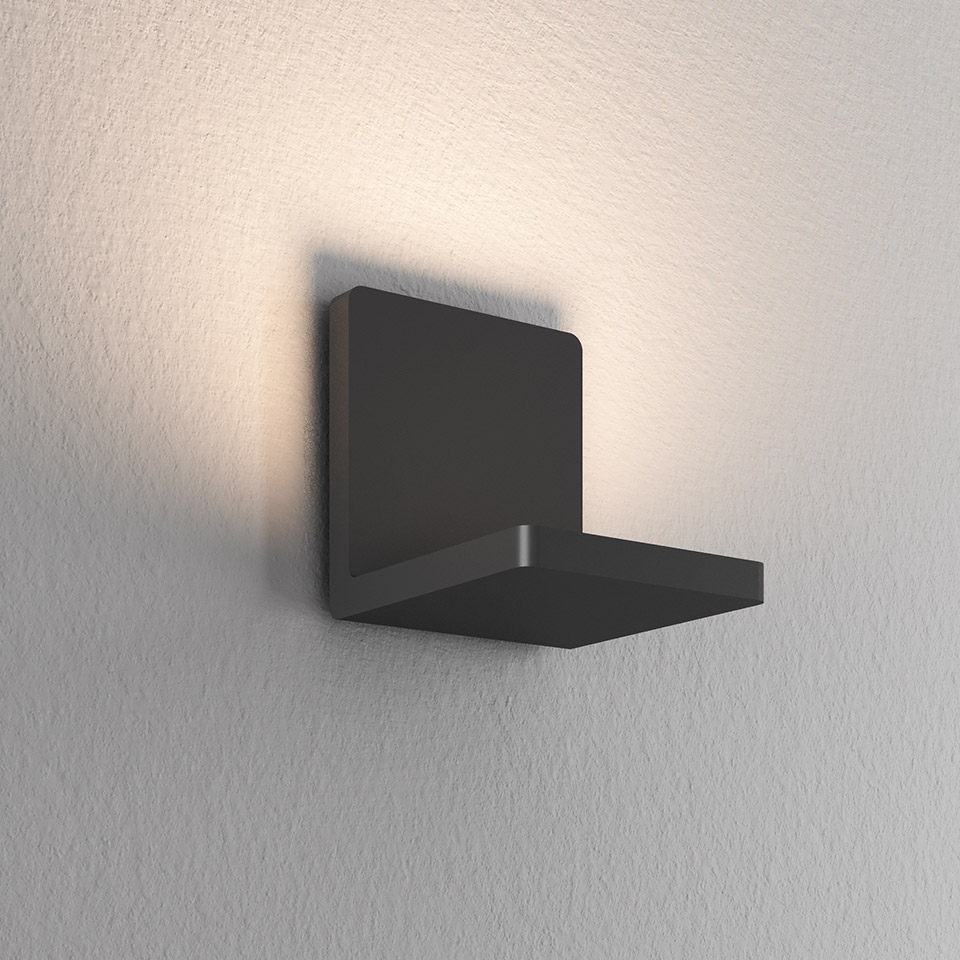 Artemide Ulrich und Diotima black wall sconce with square backplate emitting warm indirect uplight against textured wall
