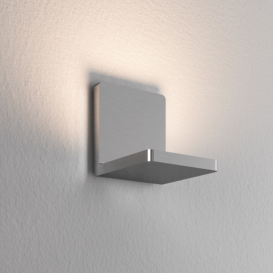 Artemide Ulrich und Diotima wall lamp: brushed aluminum cross-shaped fixture emitting warm indirect light upward on wall