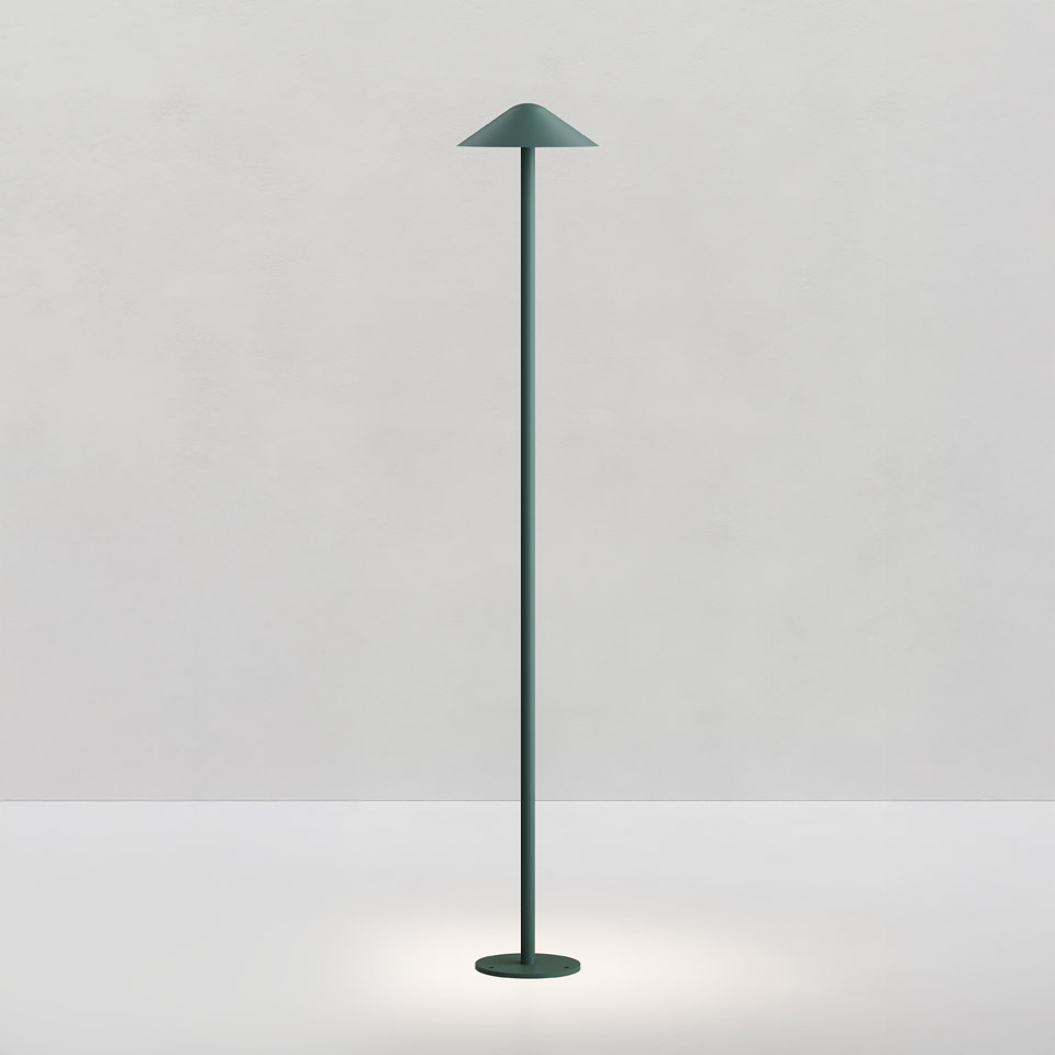Artemide Vea floor lamp in forest green, featuring a slender stem, circular base, and conical shade emitting downward light