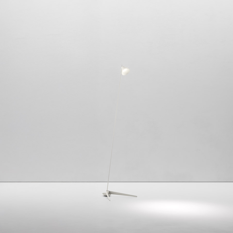 Artemide Vea floor lamp: slender white stem with tripod base and small adjustable spherical head casting a focused light pool