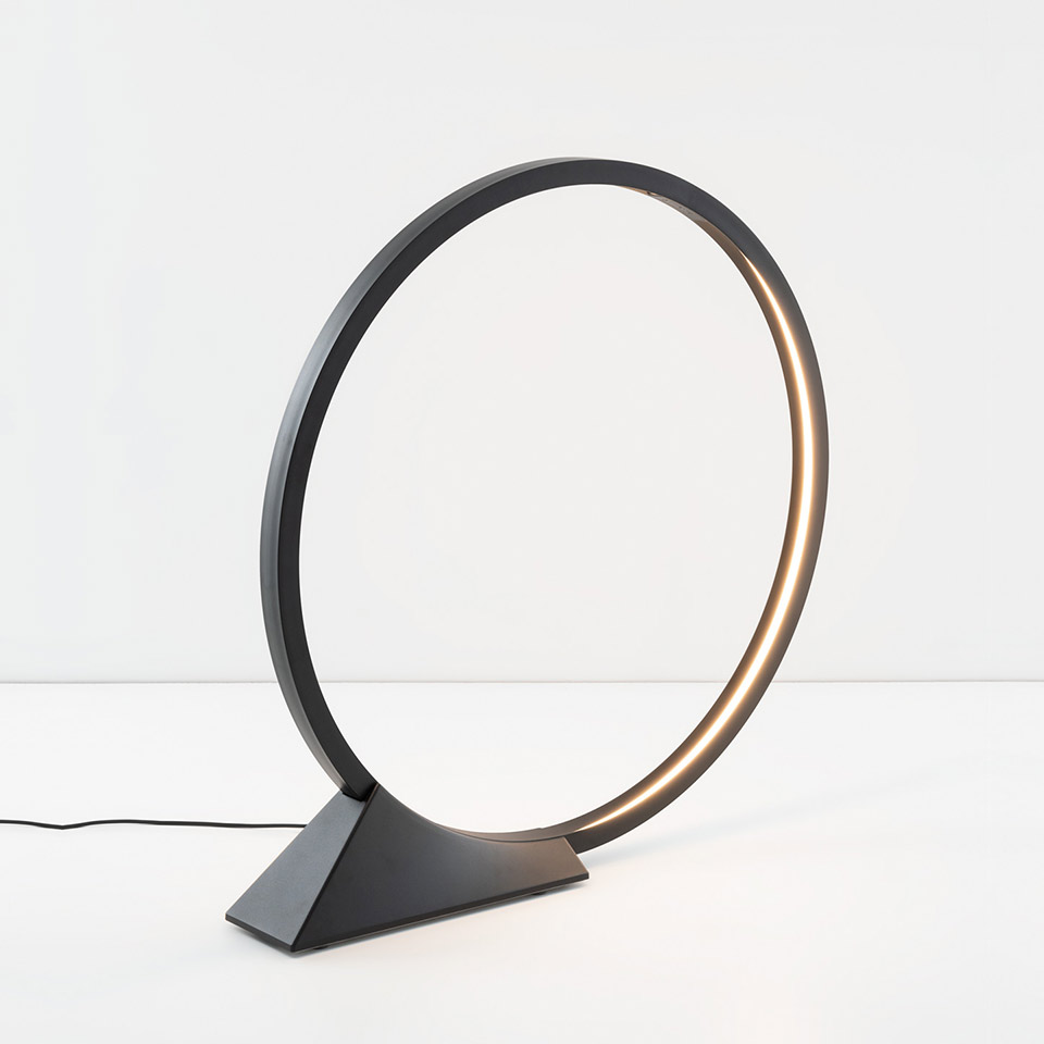 Artemide O table lamp: circular LED ring in matte black on a triangular base, emitting warm light along its inner edge - 2