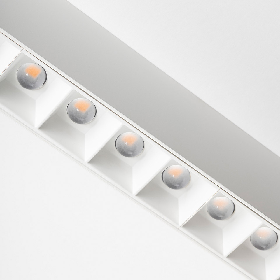 Artemide A.39 ceiling light: white linear fixture with six recessed square-framed LED lenses emitting warm directional light