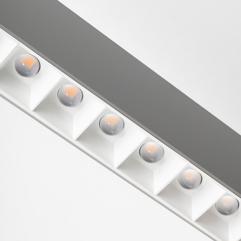 Artemide A.39 ceiling fixture close-up showing a row of six warm LED refractive lenses in white square housings on a linear profile