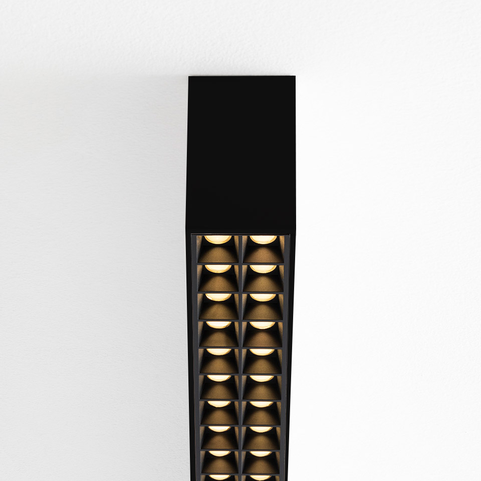 Artemide A.39 ceiling suspension lamp in black with two rows of microrefractive LED modules emitting warm golden light