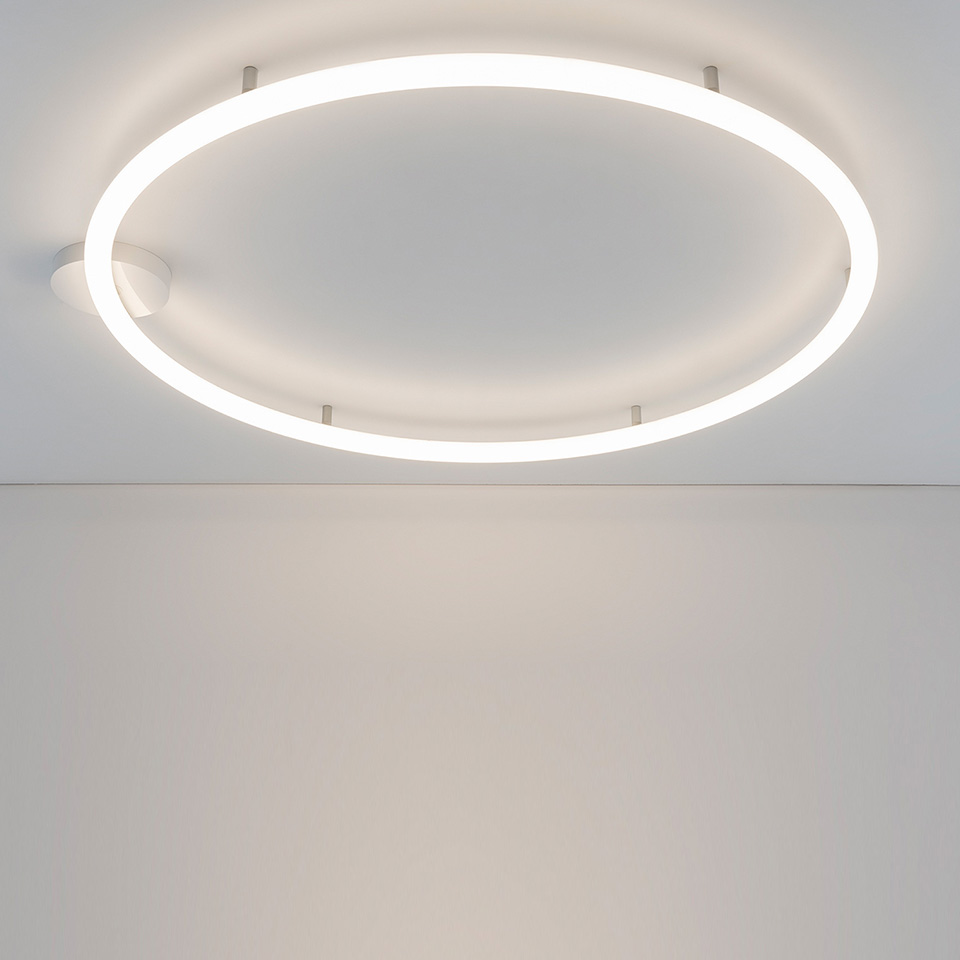 Artemide Alphabet of Light Circular ceiling lamp: large luminous white ring mounted flush on white ceiling, emitting soft diffused light