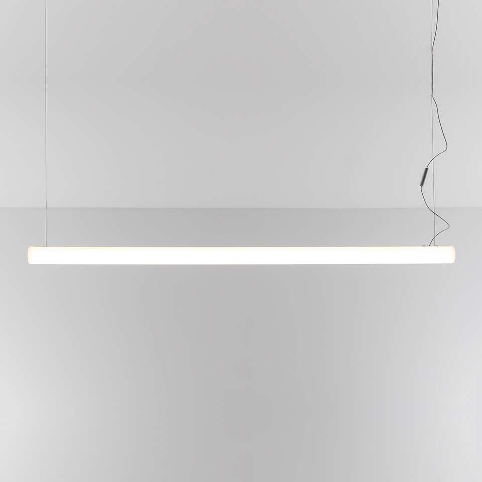 Artemide Alphabet of Light Linear pendant lamp: slim horizontal white tube emitting warm diffused light, suspended by thin cables