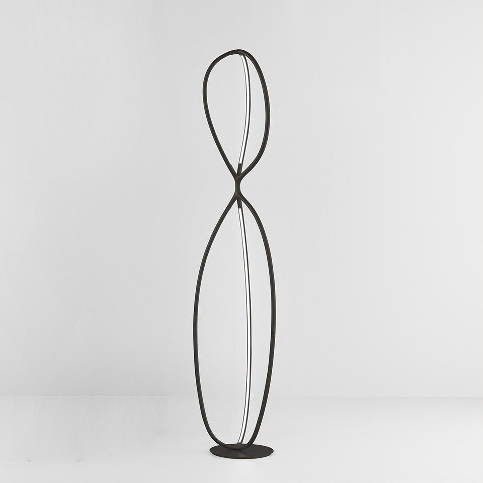 Artemide Arrival floor lamp: tall black metal structure with two intertwined loops forming an hourglass silhouette with integrated LED strips