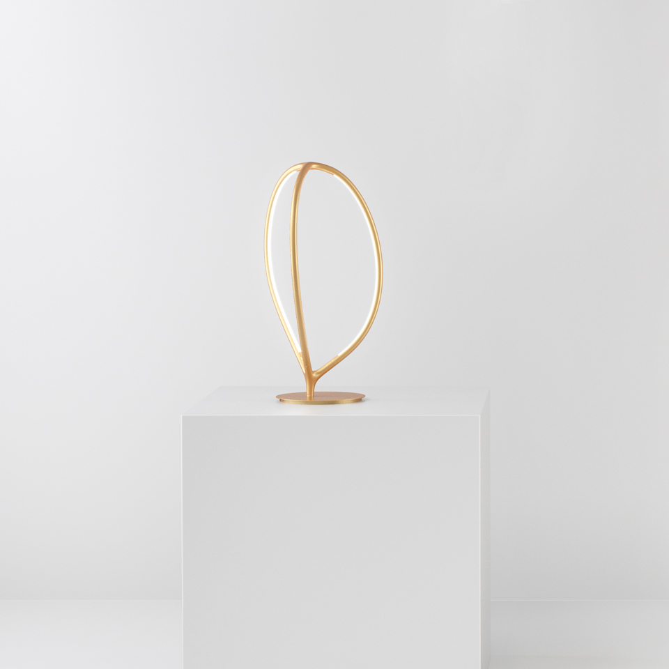 Artemide Arrival table lamp in gold finish, featuring an elegant leaf-shaped double-curve LED frame on a circular base