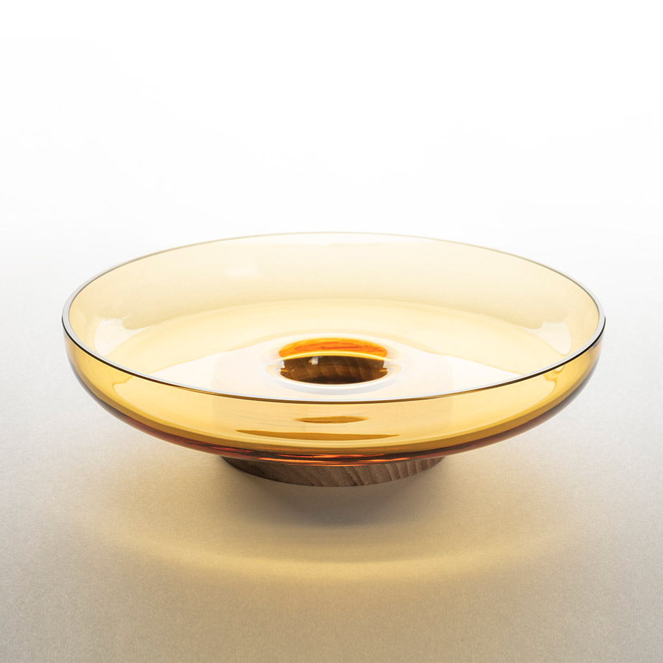 Artemide Bontà: wide shallow amber glass bowl with concave center, warm golden tones, designed as a decorative lighting diffuser