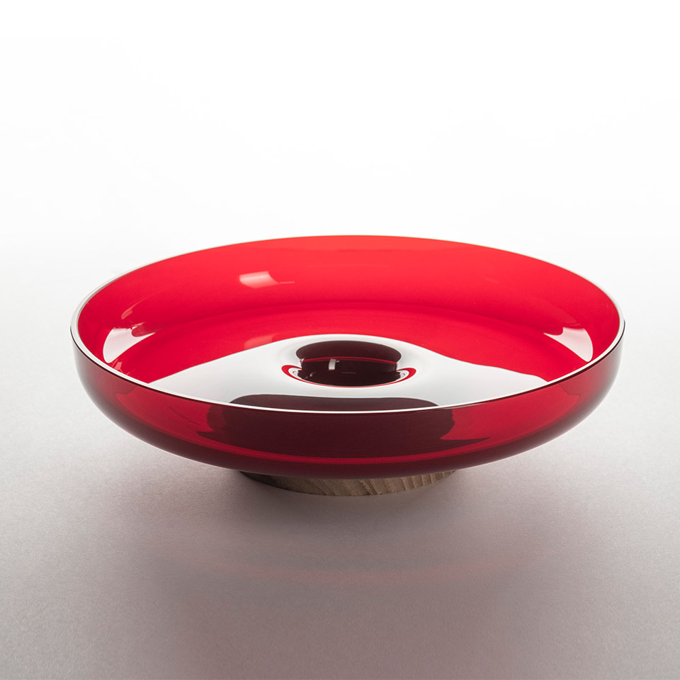 Artemide Bontà bowl-shaped lamp diffuser in glossy red glass with central opening, resting on a natural wood base