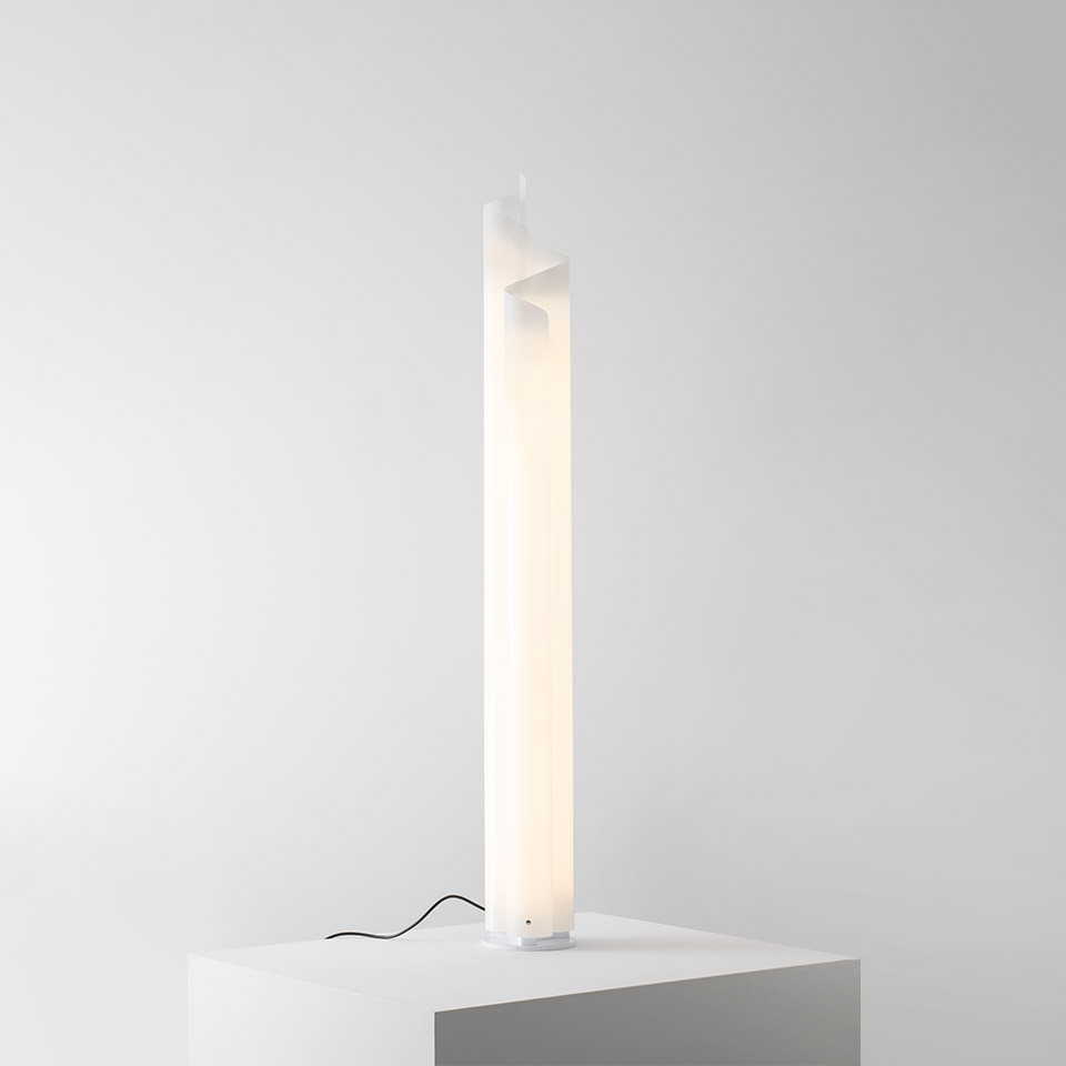 Artemide Chimera floor lamp: tall vertical white opal diffuser with sculptural twisted top, emitting warm diffused light