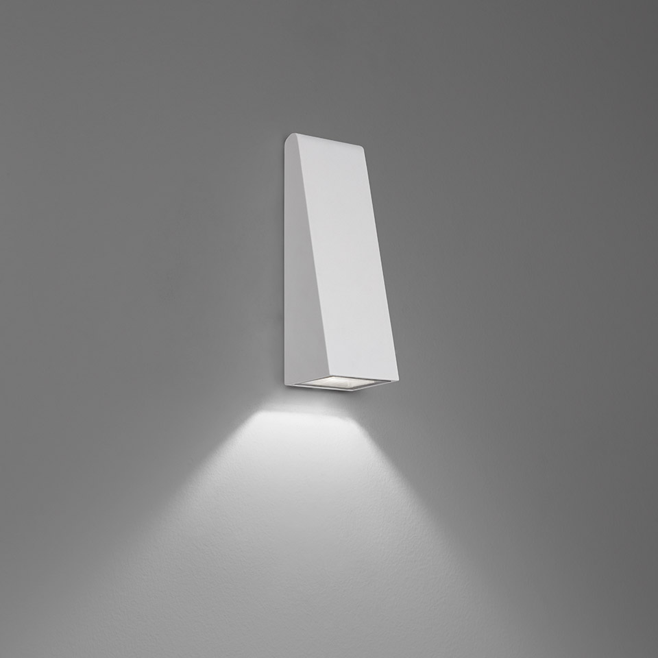 Artemide Cuneo wall light: white trapezoidal body mounted on wall, emitting focused downward LED beam