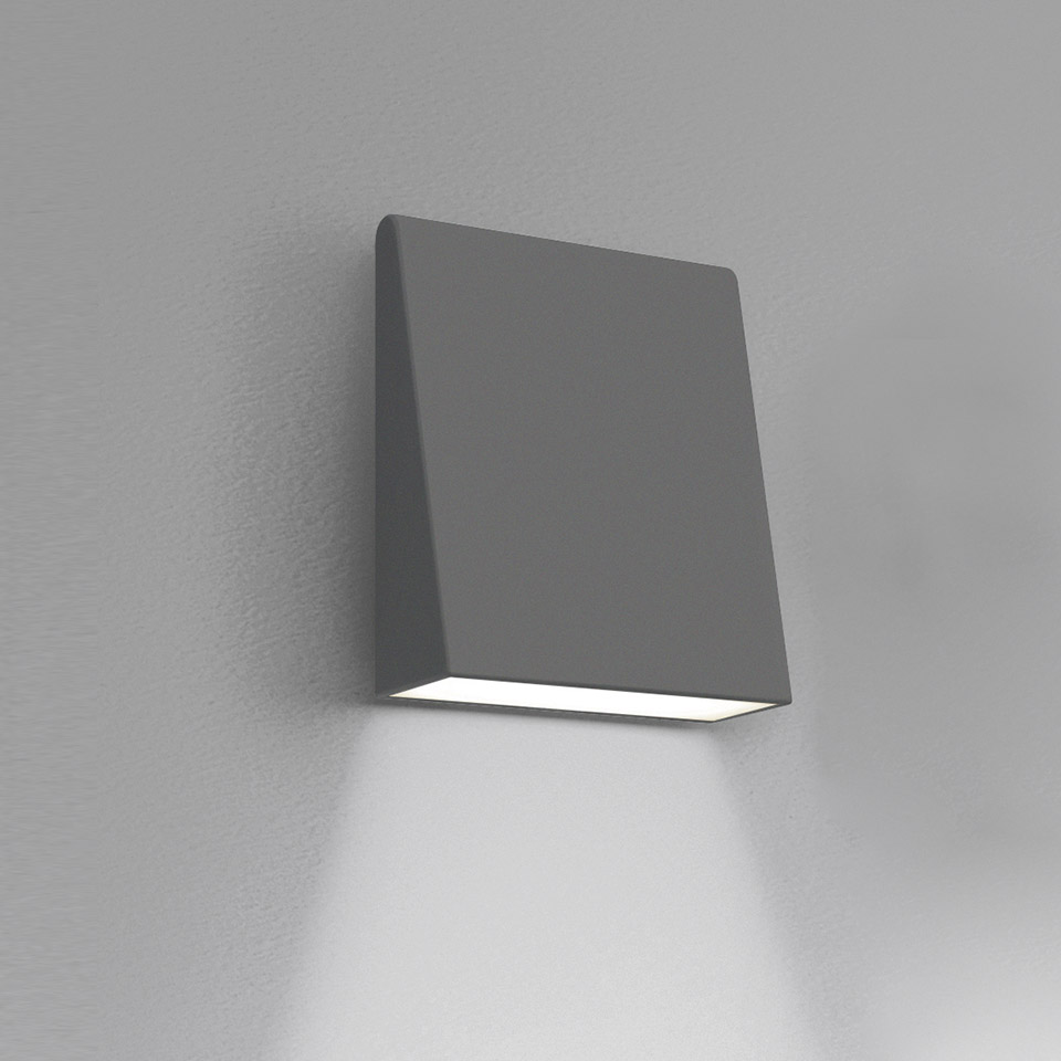 Artemide Cuneo wall light, compact square grey body, emitting downward white light beam mounted on grey wall