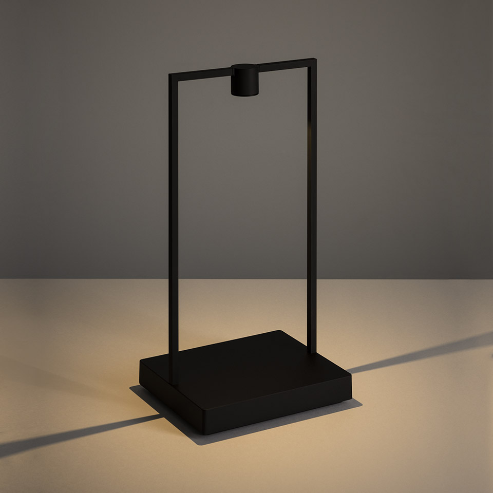 Artemide Curiosity table lamp in matte black: rectangular metal frame with downward LED spotlight on a square base