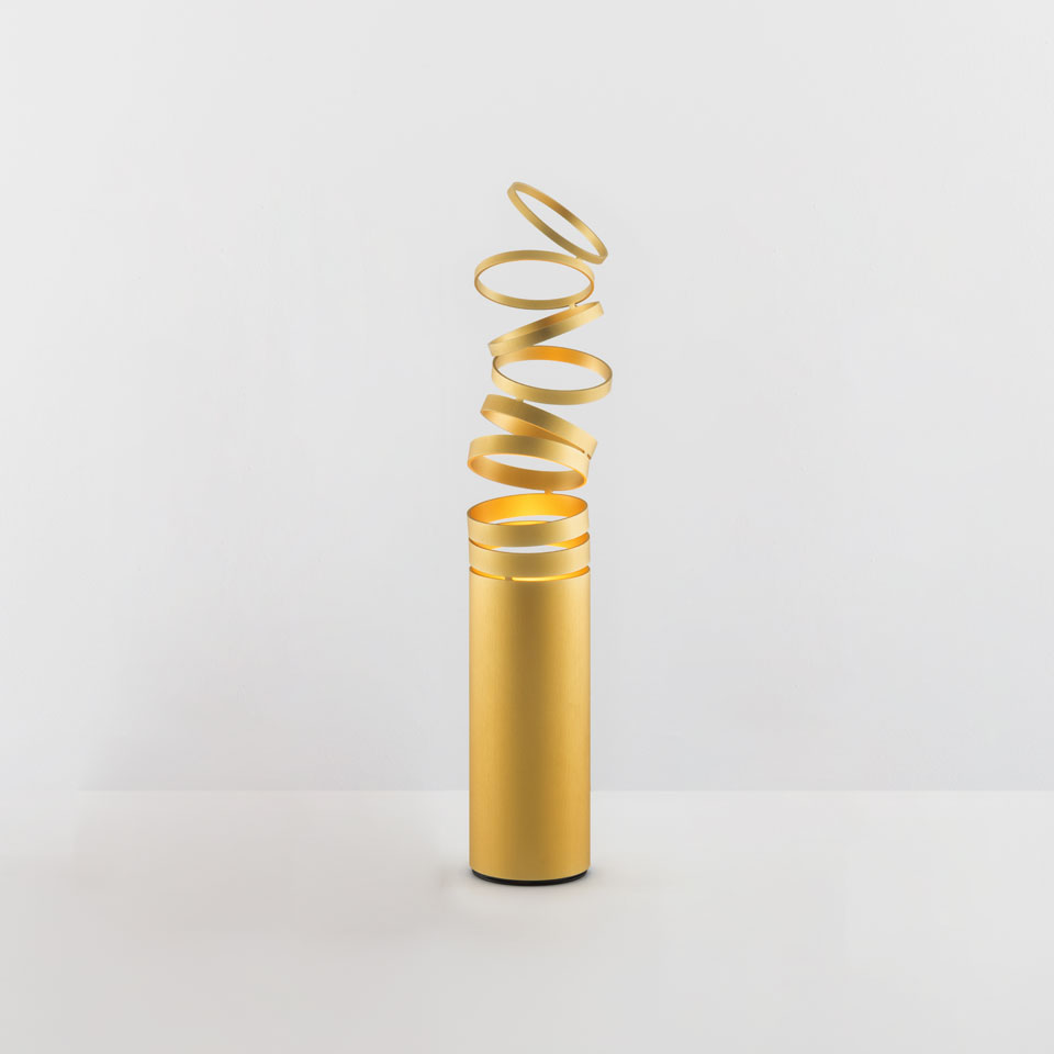Artemide Decomposé Light Tavolo table lamp in gold, featuring a cylindrical base with an upward spiraling ribbon shade.