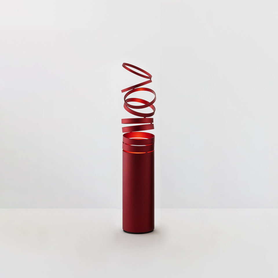 Artemide Decomposé Light Tavolo table lamp in red, cylindrical base with spiraling aluminum ribbon diffuser emitting warm light