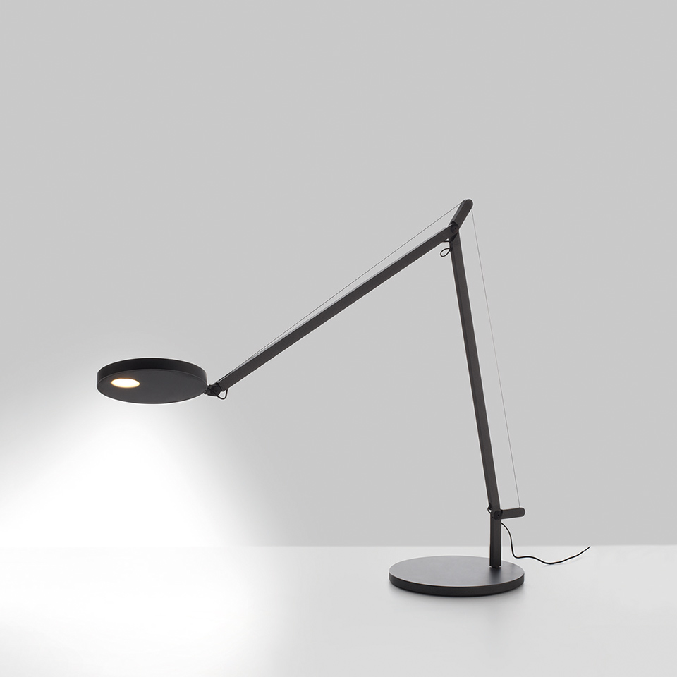 Artemide Demetra Tavolo desk lamp in black, with articulated arm, tension cable, round LED head, and circular base.
