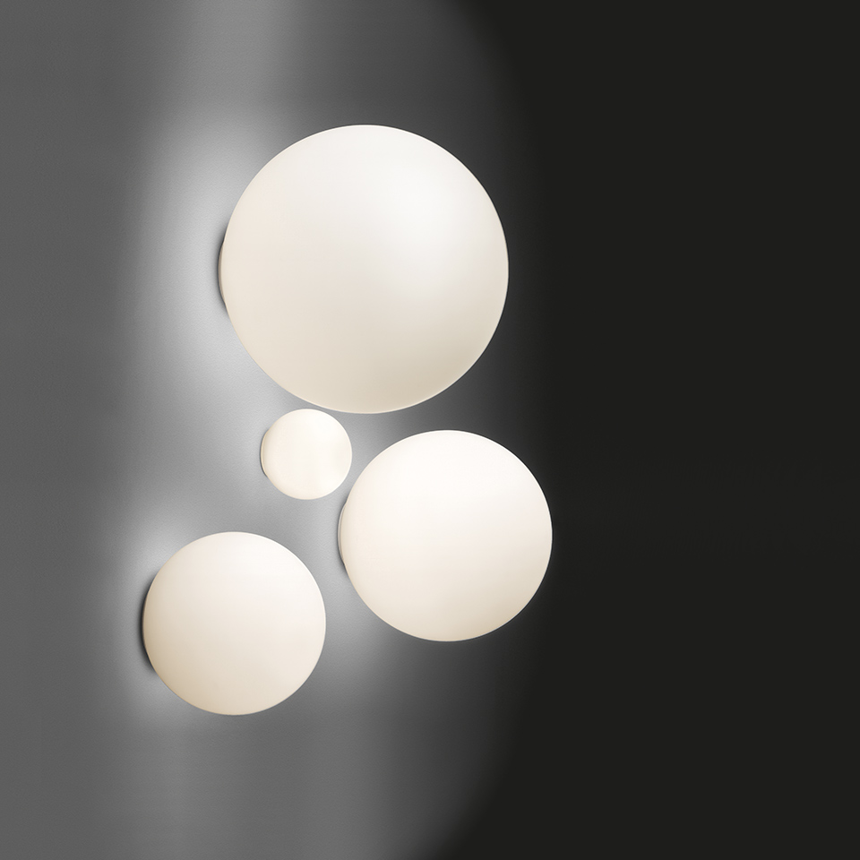 Four Artemide Dioscuri wall/ceiling lamps in different sizes, opal white glass spheres mounted on a dark wall creating a constellation effect