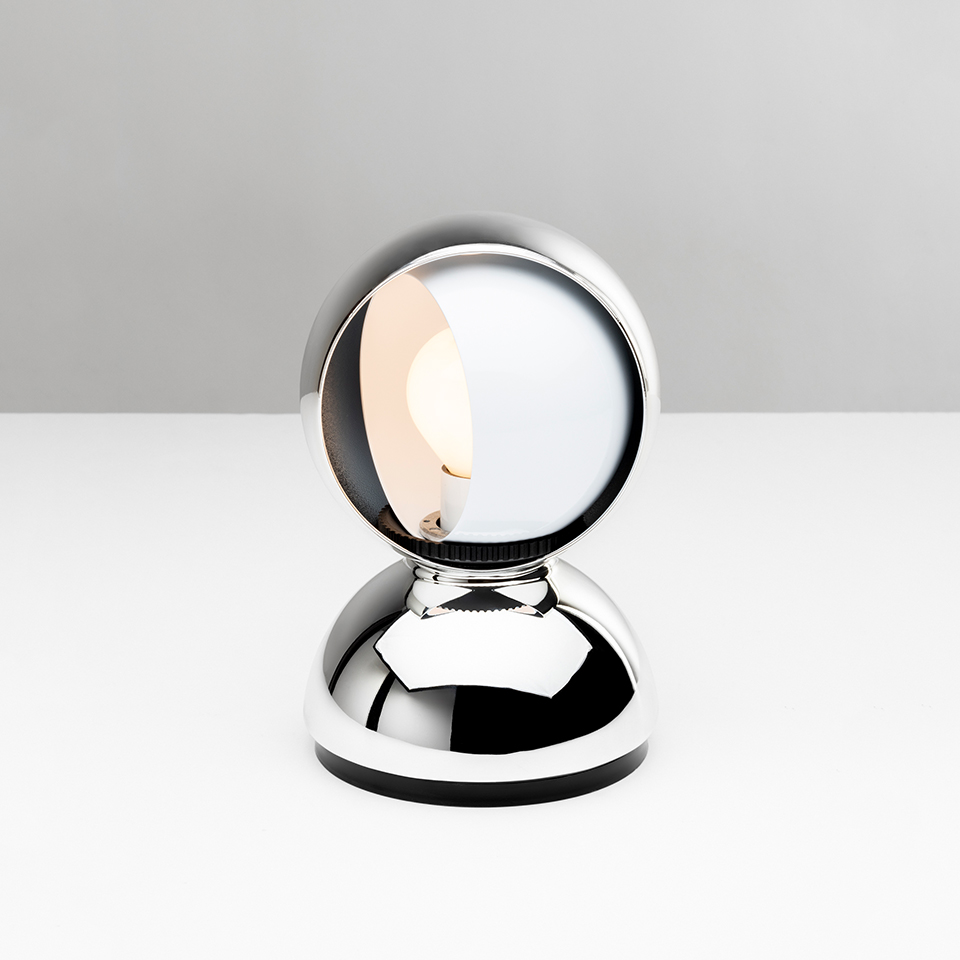 Artemide Eclisse table lamp in chrome finish, featuring a spherical rotating shade on a rounded base, revealing a warm inner light