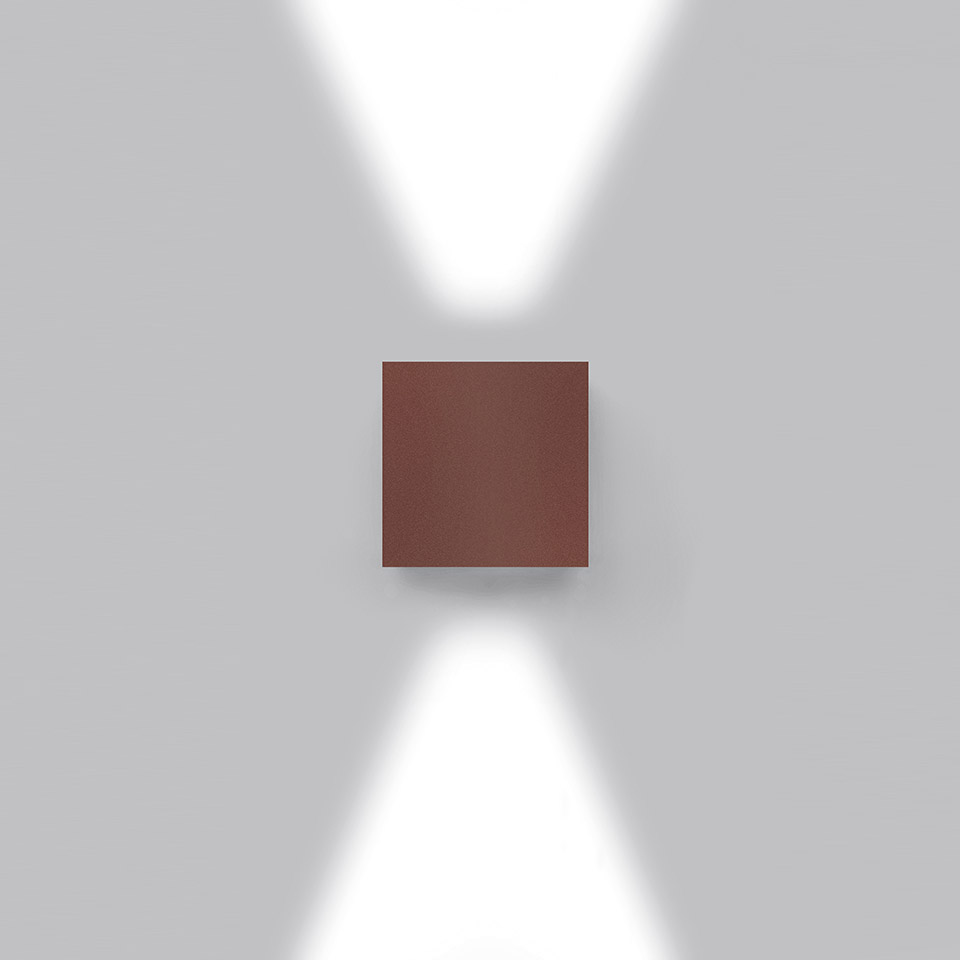 Effetto wall light by Artemide: rust-brown square body emitting two diverging beams upward and downward on a grey wall