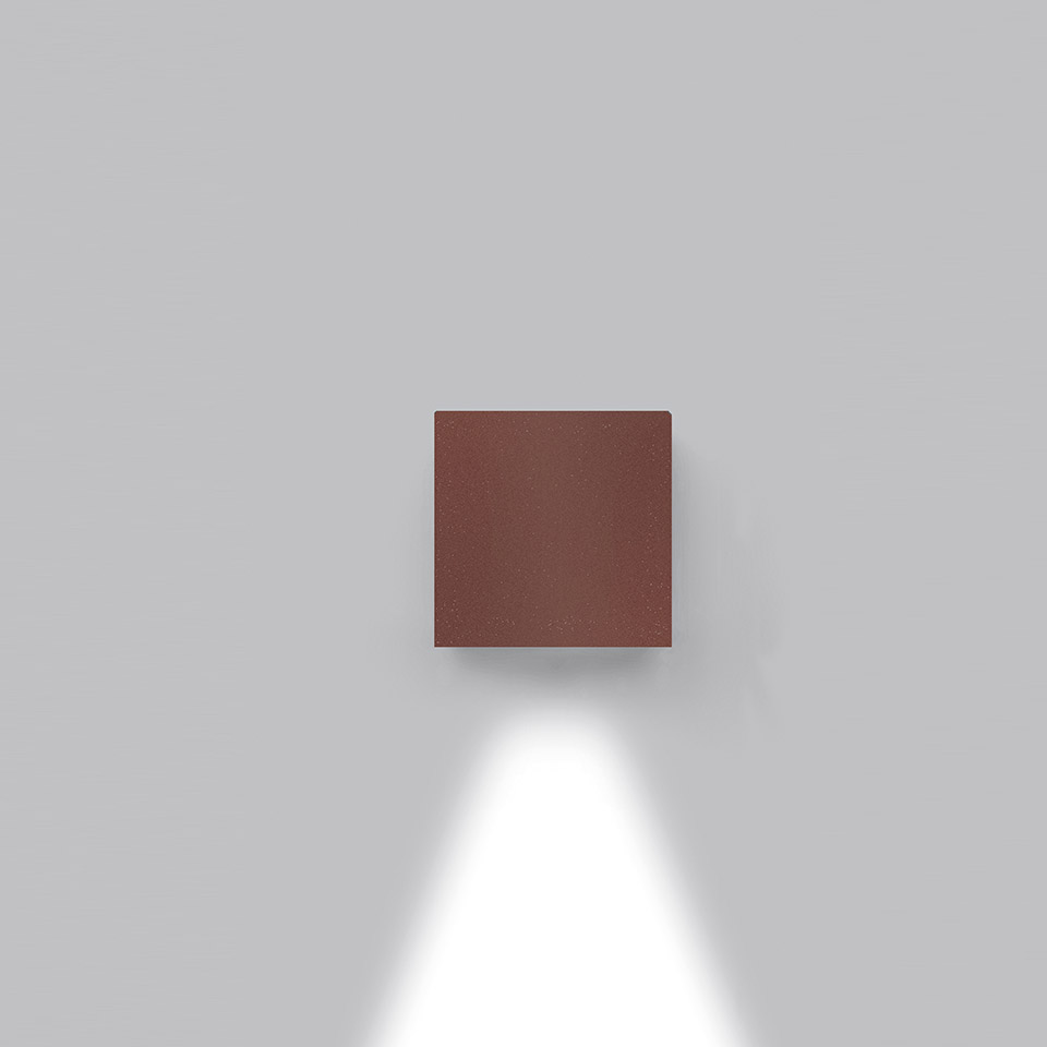 Effetto wall light by Artemide: compact square rust-red fixture emitting a downward directed beam of white light on a grey wall