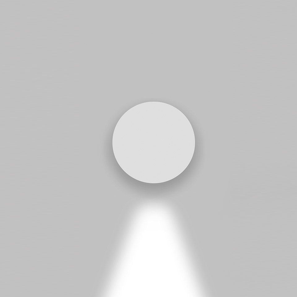 Artemide Effetto wall light, round white fixture mounted on wall, emitting a downward directional beam of light