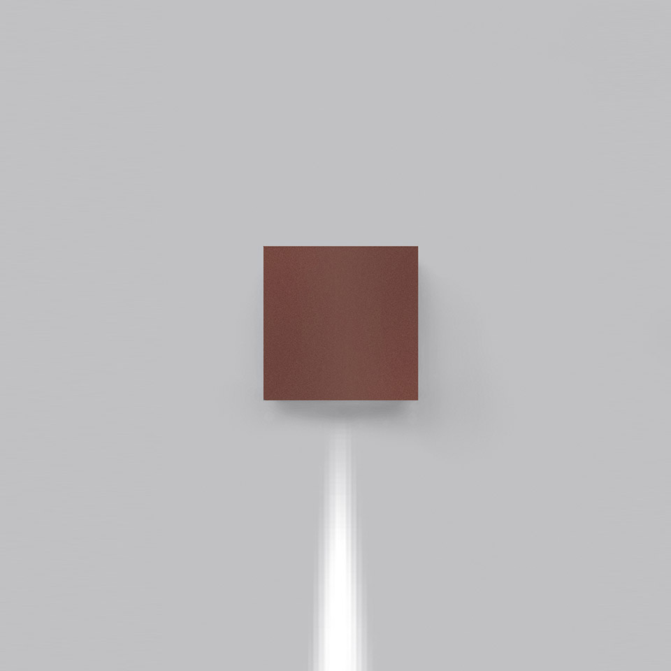 Effetto wall lamp in terracotta finish, square body mounted on grey wall, emitting a focused downward beam of white light