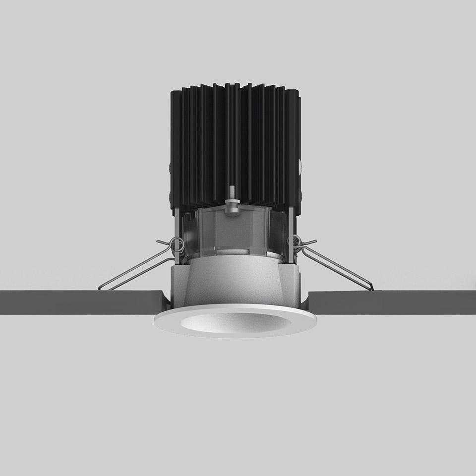 Artemide Everything 55 recessed LED downlight with white round trim, black heat sink fins, and spring-clip ceiling mounting system