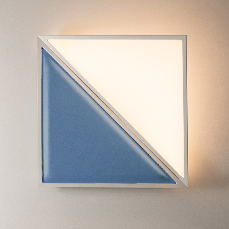 Artemide Flexia wall lamp: square white frame with warm LED light behind upper-right triangle, blue ceramic panel on lower-left triangle