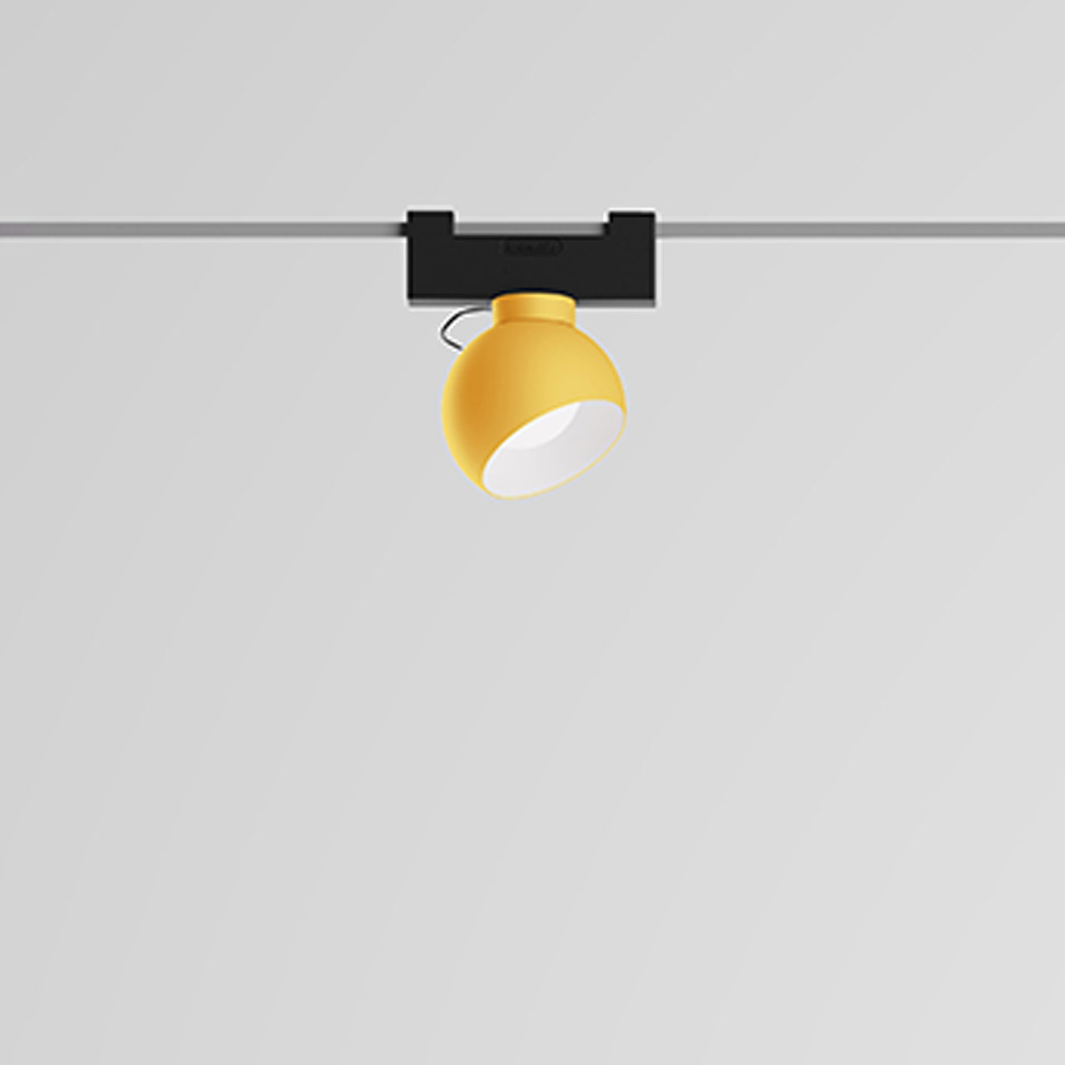Artemide Funivia track spotlight with yellow spherical shade mounted on a black track rail, directed downward