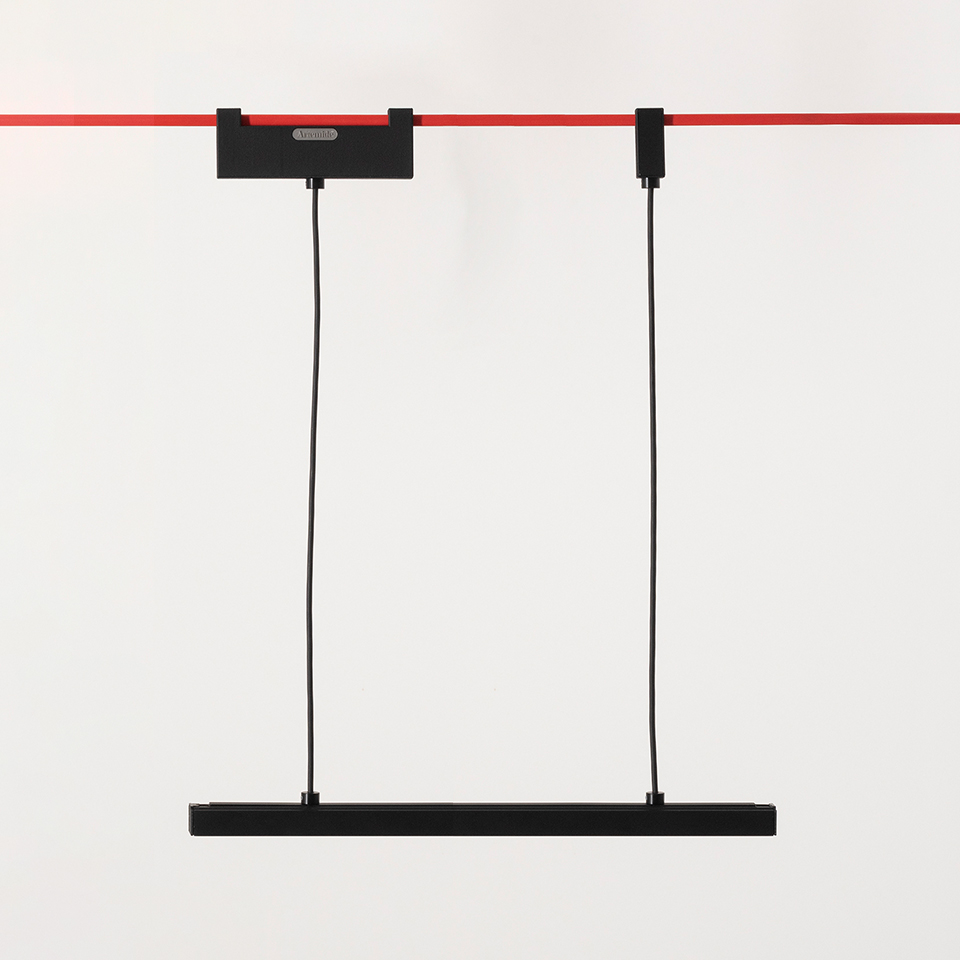 Artemide Funivia pendant lamp: slim black LED bar suspended by two black cables from a red ceiling rail system
