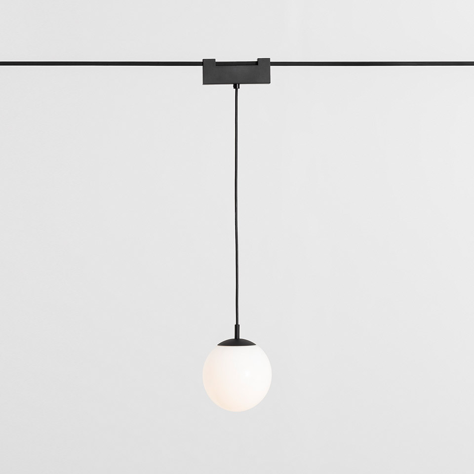 Artemide Funivia pendant lamp: matte white spherical glass globe on black cord suspended from a black track rail mount