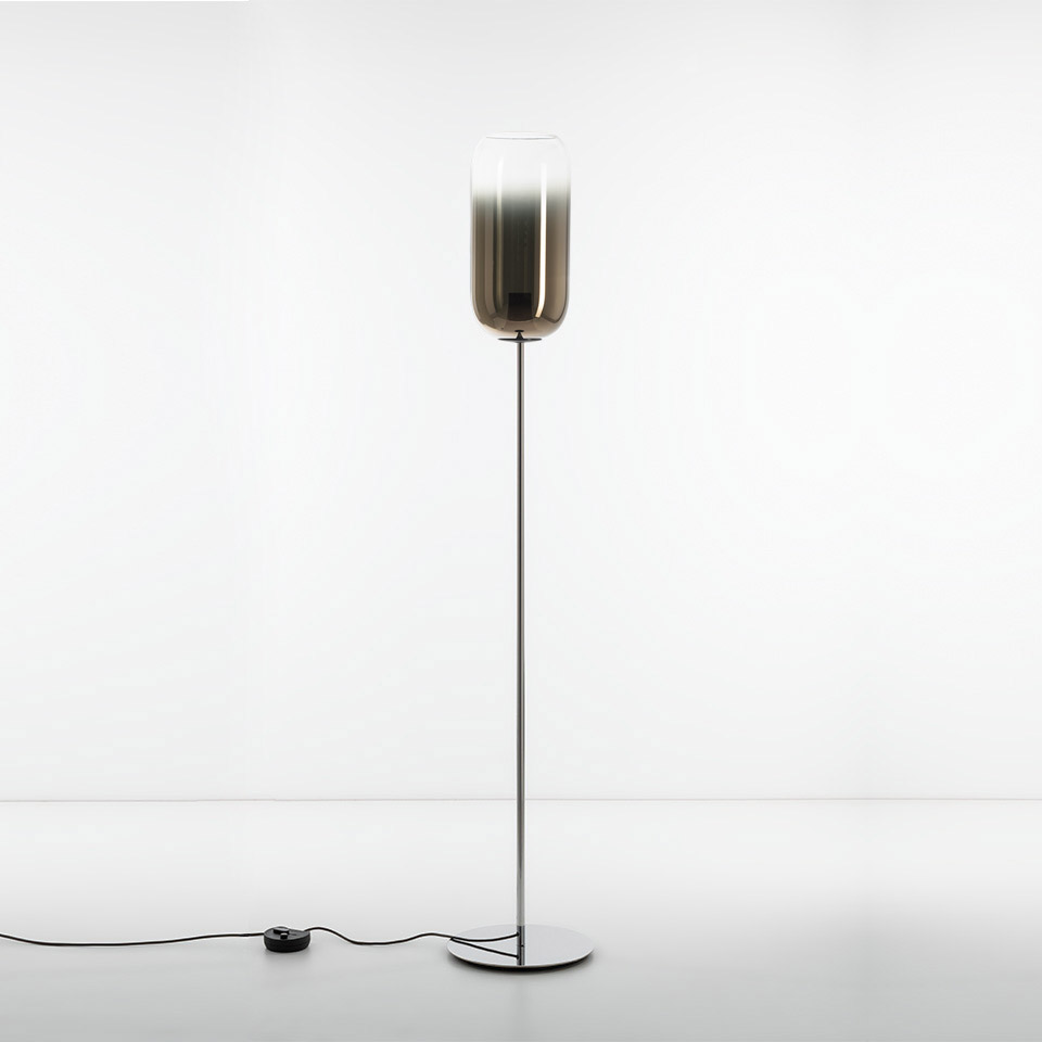 Artemide Gople floor lamp: tall chrome stem with round base, smoky gradient glass diffuser, pill-shaped shade, foot dimmer switch