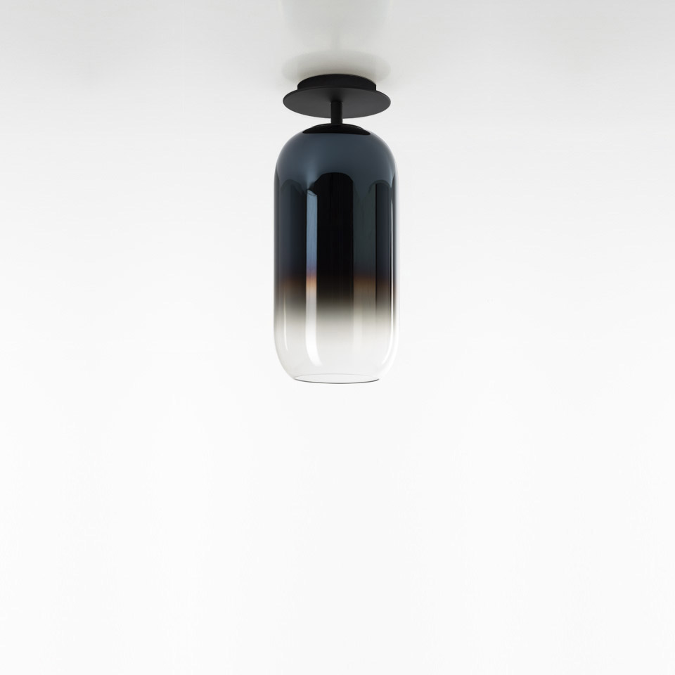 Artemide Gople ceiling lamp with elongated capsule-shaped glass shade, gradient from black to clear, mounted on black ceiling plate