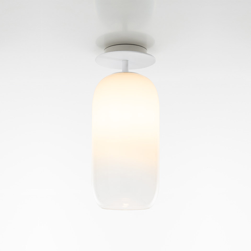 Artemide Gople ceiling lamp with oval opal white glass diffuser and white metal mount, emitting warm diffused light