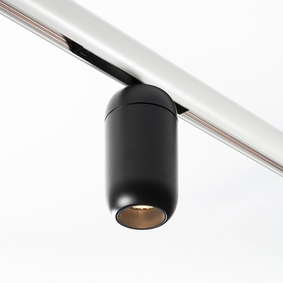 Artemide Gople System track spotlight: compact black cylindrical LED fixture mounted on a silver rail, angled downward