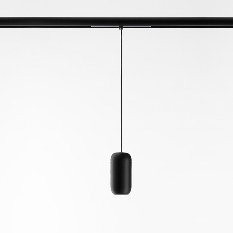 Artemide Gople System: black capsule-shaped pendant lamp suspended by a thin cable from a black ceiling track rail