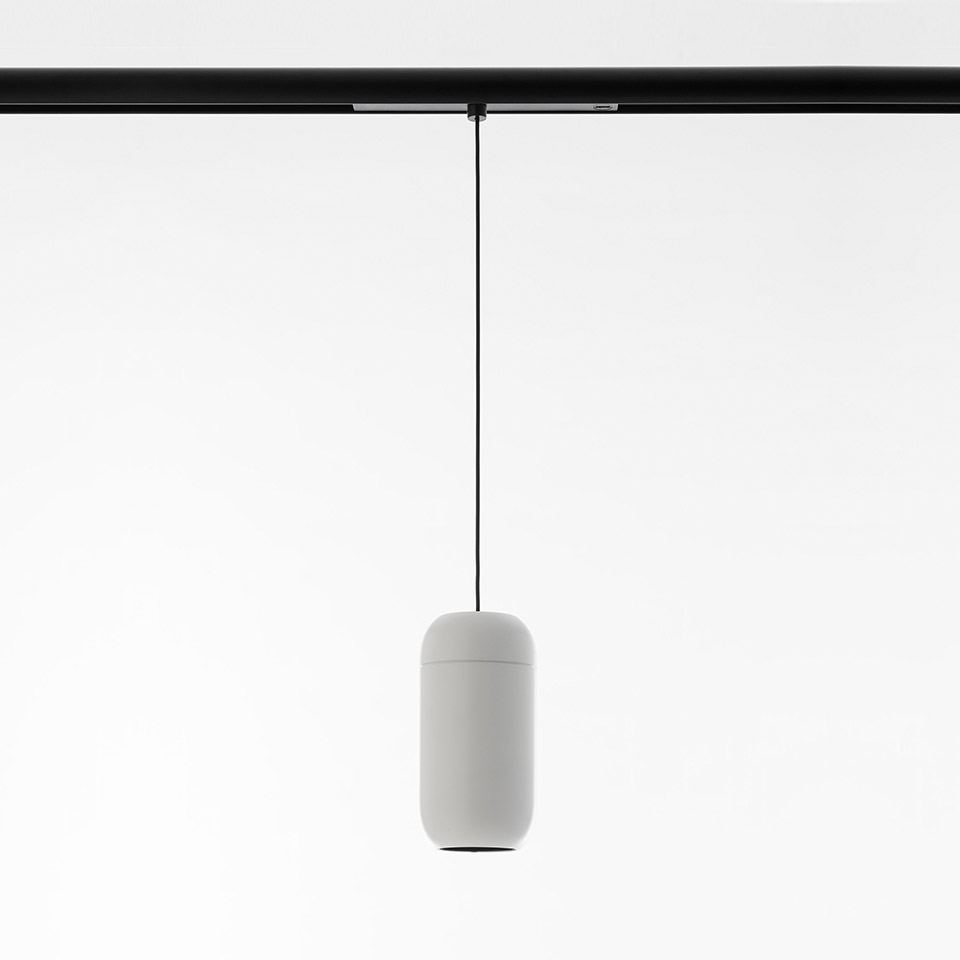 Artemide Gople System pendant lamp: white capsule-shaped diffuser suspended by black cable from a black track rail
