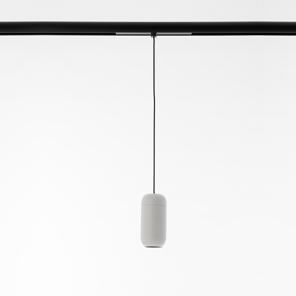 Artemide Gople System pendant lamp: small white capsule-shaped shade suspended by thin black cable from a black ceiling track