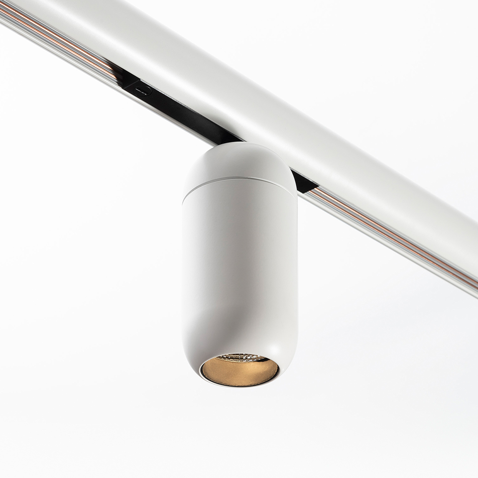 Artemide Gople System track spotlight: white cylindrical LED fixture with gold inner reflector mounted on a white ceiling track rail
