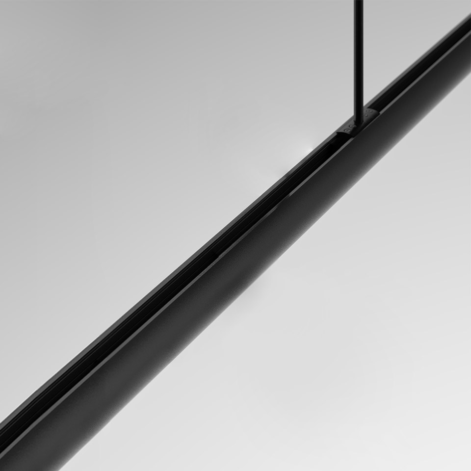 Close-up of Artemide Gople System linear pendant: sleek black cylindrical tube suspended by thin black rod against grey background
